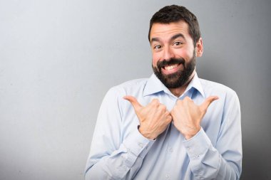 Dokulu arka plan üzerinde başparmak ile sakallı yakışıklı adam