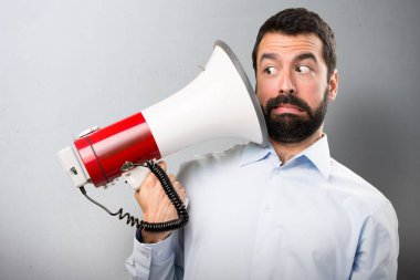 Bir megafon dokulu arka plan üzerinde tutarak sakallı yakışıklı adam