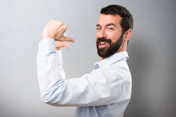 Knappe man met baard die trots op zichzelf op gestructureerde achtergrond — Stockfoto