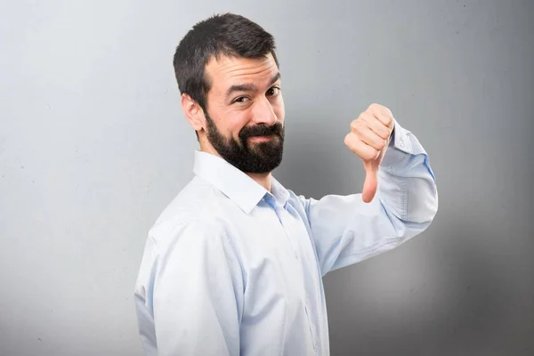 Bonito homem com barba fazendo mau sinal no fundo texturizado — Fotografia de Stock