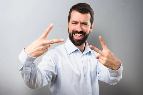 Bonito homem com barba fazendo gesto de vitória em fundo texturizado — Fotografia de Stock