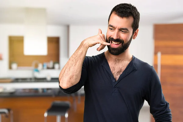 Bonito homem com barba fazendo gesto de telefone dentro de casa — Fotografia de Stock