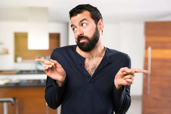 Bonito homem com barba apontando para as laterais com dúvidas i — Fotografia de Stock