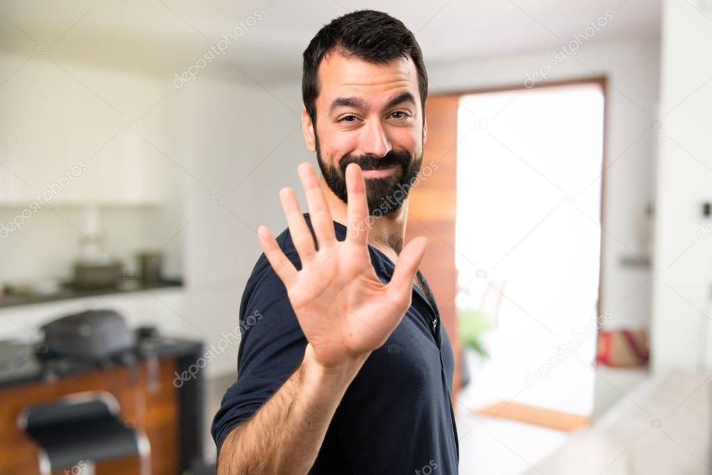 Handsome man with beard counting five inside house