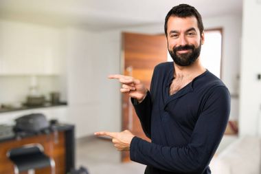 Evin içinde lateral işaret eden sakallı yakışıklı adam