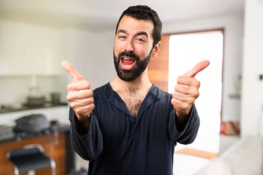 Başparmak ile sakallı yakışıklı adam yukarı evin içinde