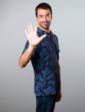 Esmer adam beş gri arka plan üzerinde sayma