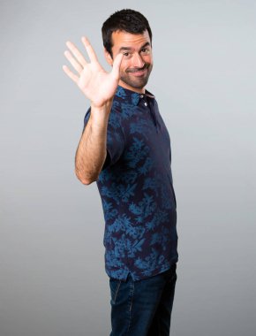 Esmer adam gri arka plan üzerinde selamlayan