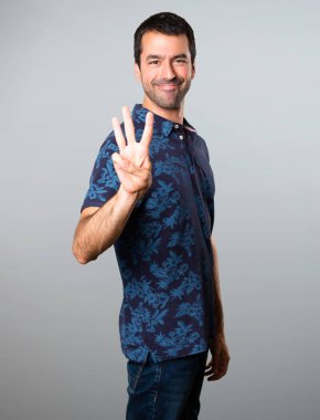 Esmer adam üç gri arka plan üzerinde sayma