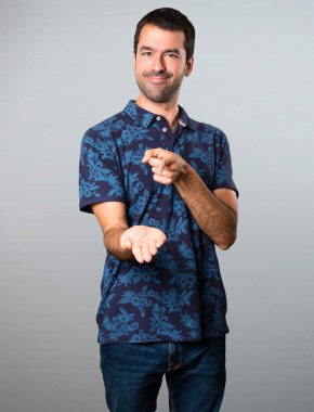 Esmer adam bir şey gri arka plan üzerinde tutan