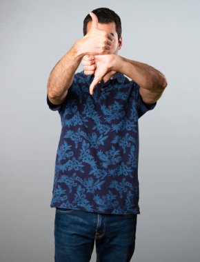 Esmer adam iyi-kötü işareti gri arka plan üzerinde yapma