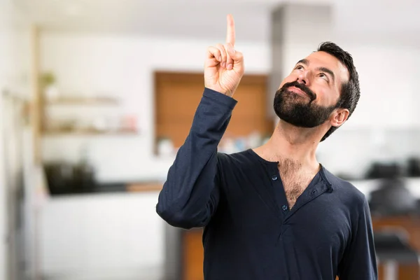 Handsome man with beard pointing up inside house