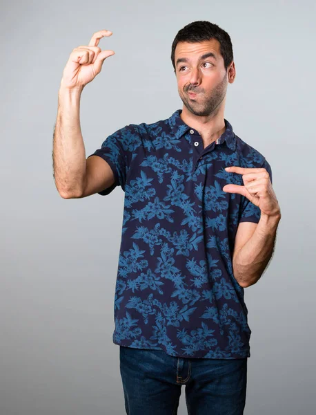 Esmer adam küçük işareti gri arka plan üzerinde yapma