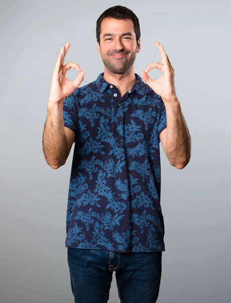 Esmer adam gri arka plan üzerinde oturum Tamam yapma