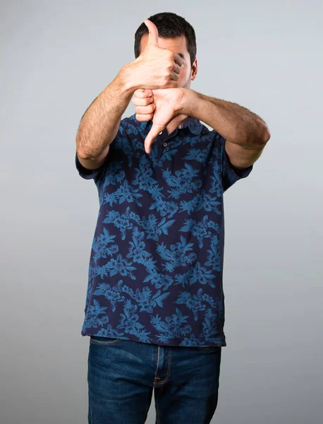 Esmer adam iyi-kötü işareti gri arka plan üzerinde yapma