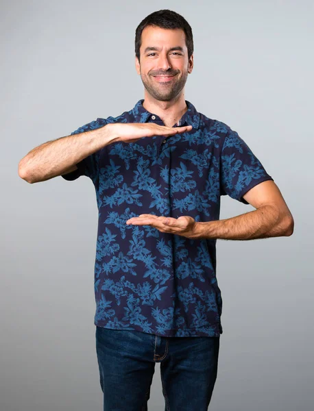 Esmer adam bir şey gri arka plan üzerinde tutan