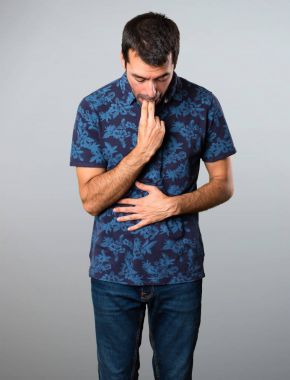 Esmer adam gri arka plan üzerine kusma jest yapma