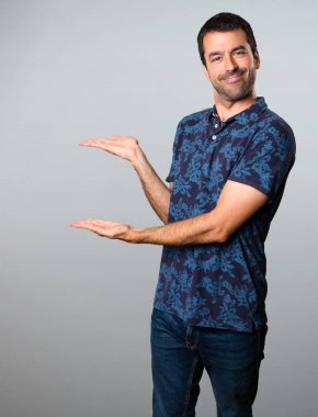 Esmer adam bir şey gri arka plan üzerinde sunulması