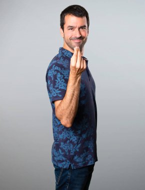 Esmer adam yapma para jest gri arka plan üzerinde