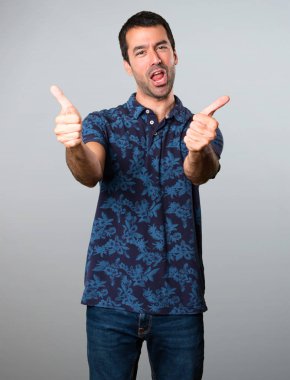 Esmer adam gri arka plan üzerinde başparmak ile