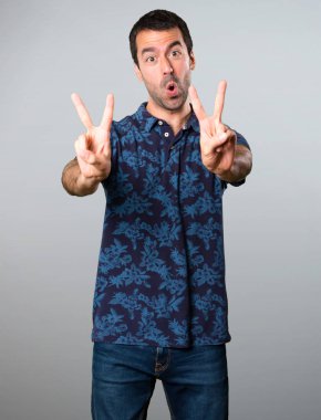 Esmer adam yapma zafer jest gri arka plan üzerinde