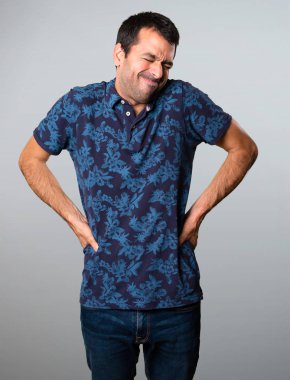 Esmer adam gri arka plan üzerinde sırt ağrısı ile