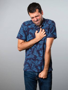 Kalp ağrısı gri arka plan üzerinde olan esmer adam