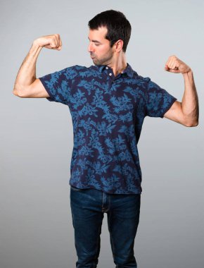 Esmer adam gri arka plan üzerinde güçlü bir jest yapma