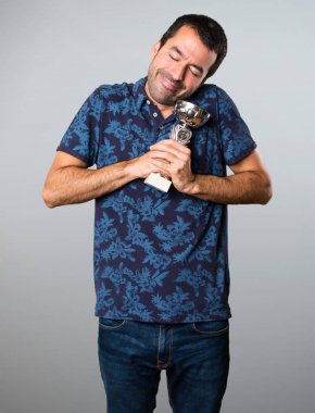 Esmer adam bir kupa gri arka plan üzerinde tutan