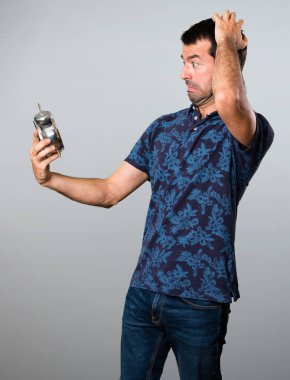 Esmer adam Vintage saat gri arka plan üzerinde tutan