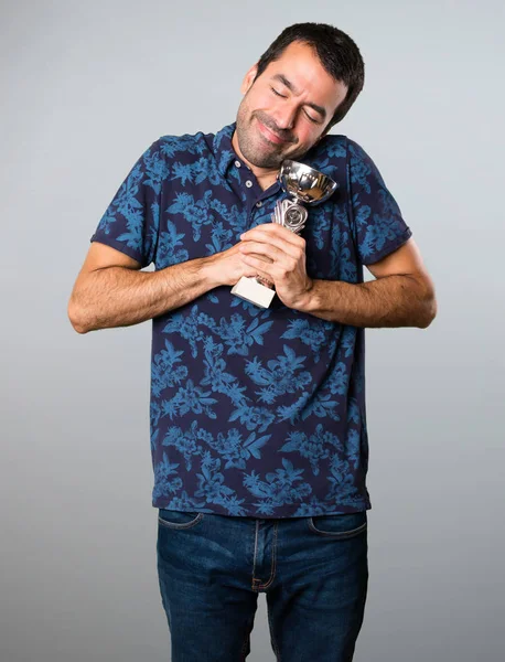 Esmer adam bir kupa gri arka plan üzerinde tutan