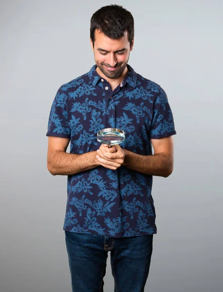 Esmer adam gri arka plan üzerinde büyüteç ile