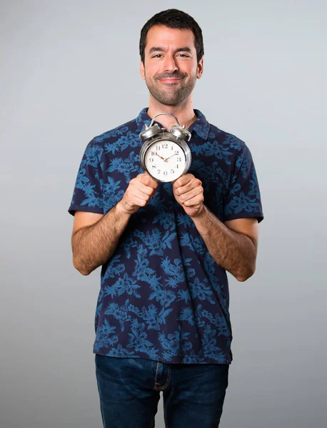 Brünette Mann hält Oldtimer-Uhr auf grauem Hintergrund — Stockfoto
