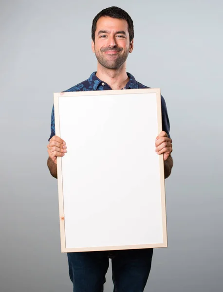 Brunette homme tenant une pancarte vide sur fond gris — Photo