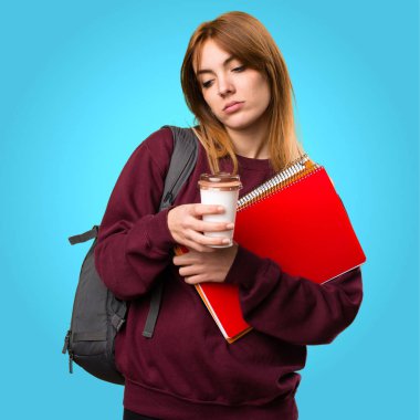 Bir fincan kahve renkli arka plan üzerinde tutan öğrenci kadın