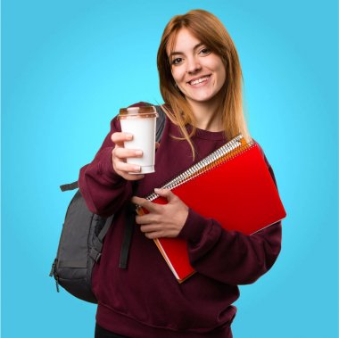 Bir fincan kahve renkli arka plan üzerinde tutan öğrenci kadın