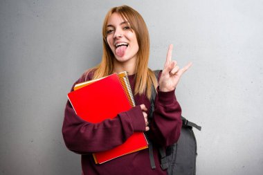 Öğrenci kadın yapma boynuz jest gri arka plan üzerinde