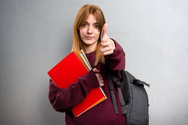 Öğrenci kadın yapım silah jest gri arka plan üzerinde