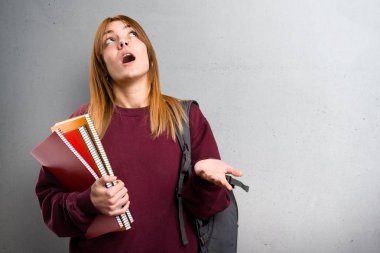 Gri arka plan üzerinde yalvaran öğrenci kadın