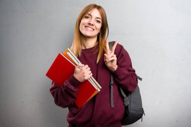 Öğrenci kadın yapma zafer jest gri arka plan üzerinde