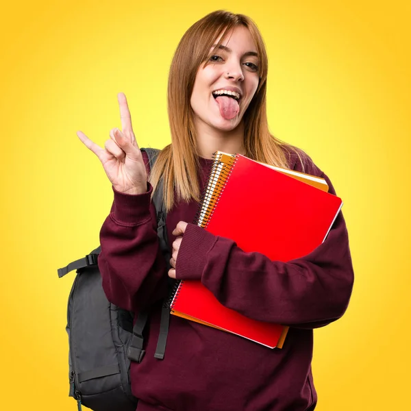 Öğrenci kadın yapma boynuz jest renkli arka plan üzerinde