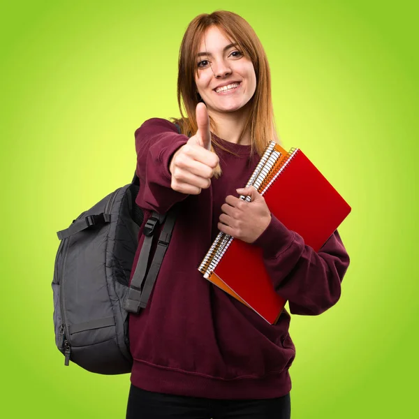 Studente donna con pollice su sfondo colorato — Foto Stock