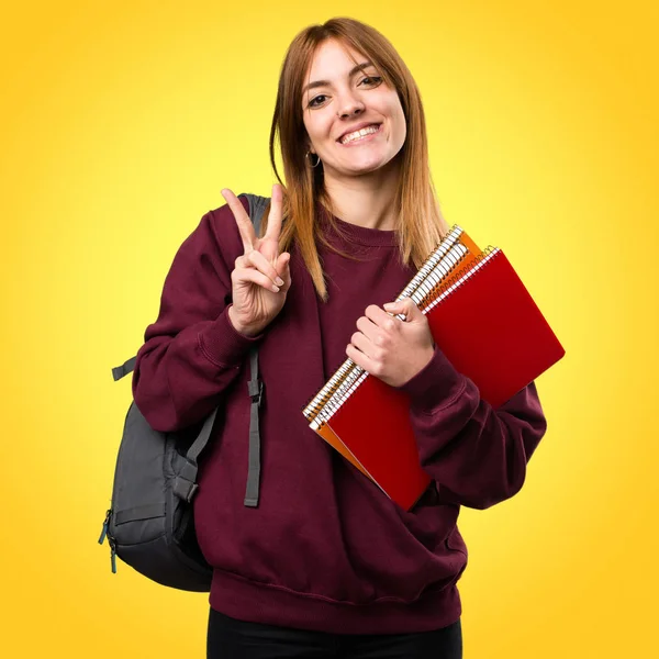 Öğrenci kadın yapma zafer jest renkli arka plan üzerinde