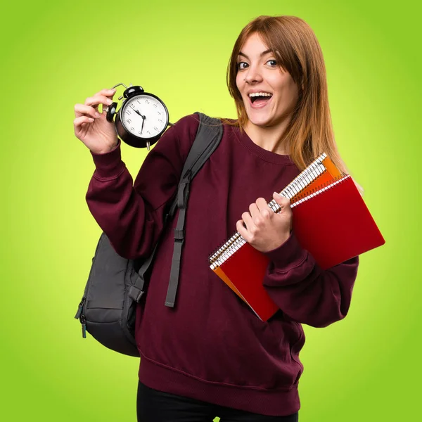 Vintage saat renkli arka plan üzerinde tutan öğrenci kadın