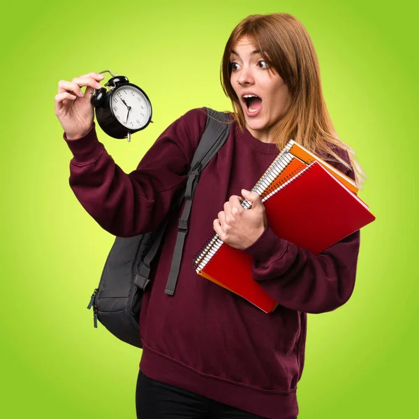 Vintage saat renkli arka plan üzerinde tutan öğrenci kadın