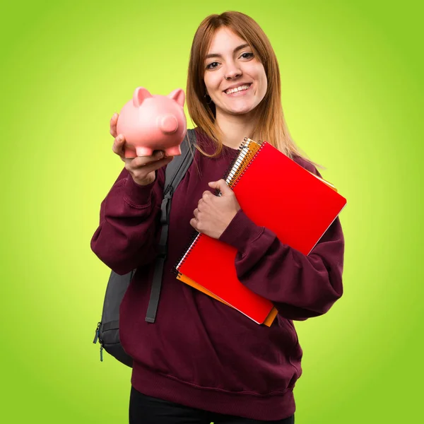 Studentka žena držící prasátko na barevné pozadí — Stock fotografie