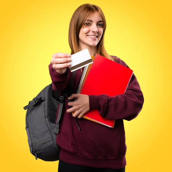 Renkli arka plan üzerinde bir kredi kartı tutan öğrenci kadın