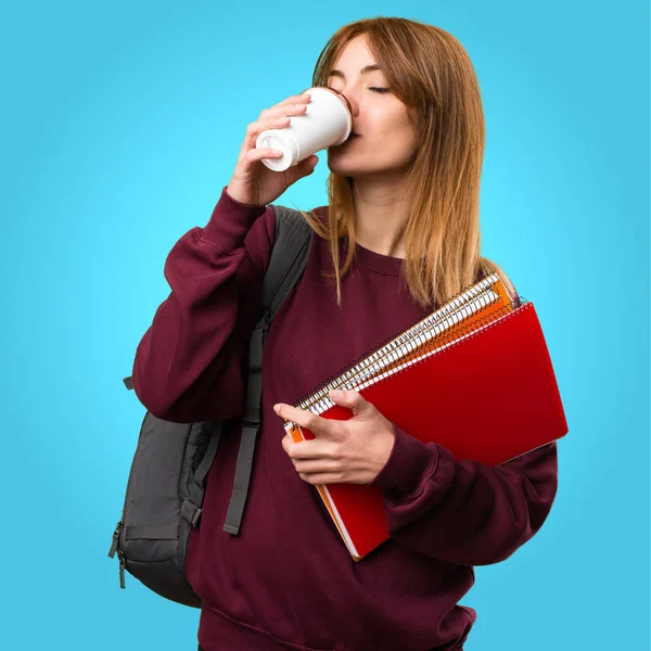 Bir fincan kahve renkli arka plan üzerinde tutan öğrenci kadın