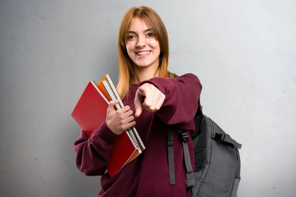 Studente donna che punta verso la parte anteriore su sfondo grigio — Foto Stock