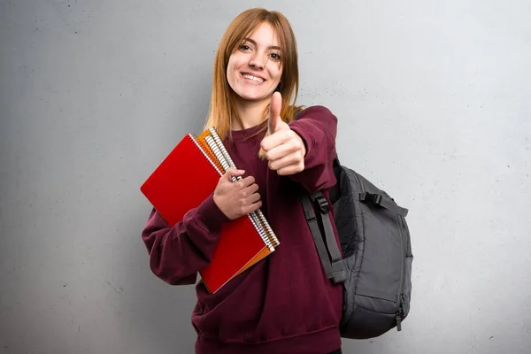 Studentin mit erhobenem Daumen auf grauem Hintergrund — Stockfoto